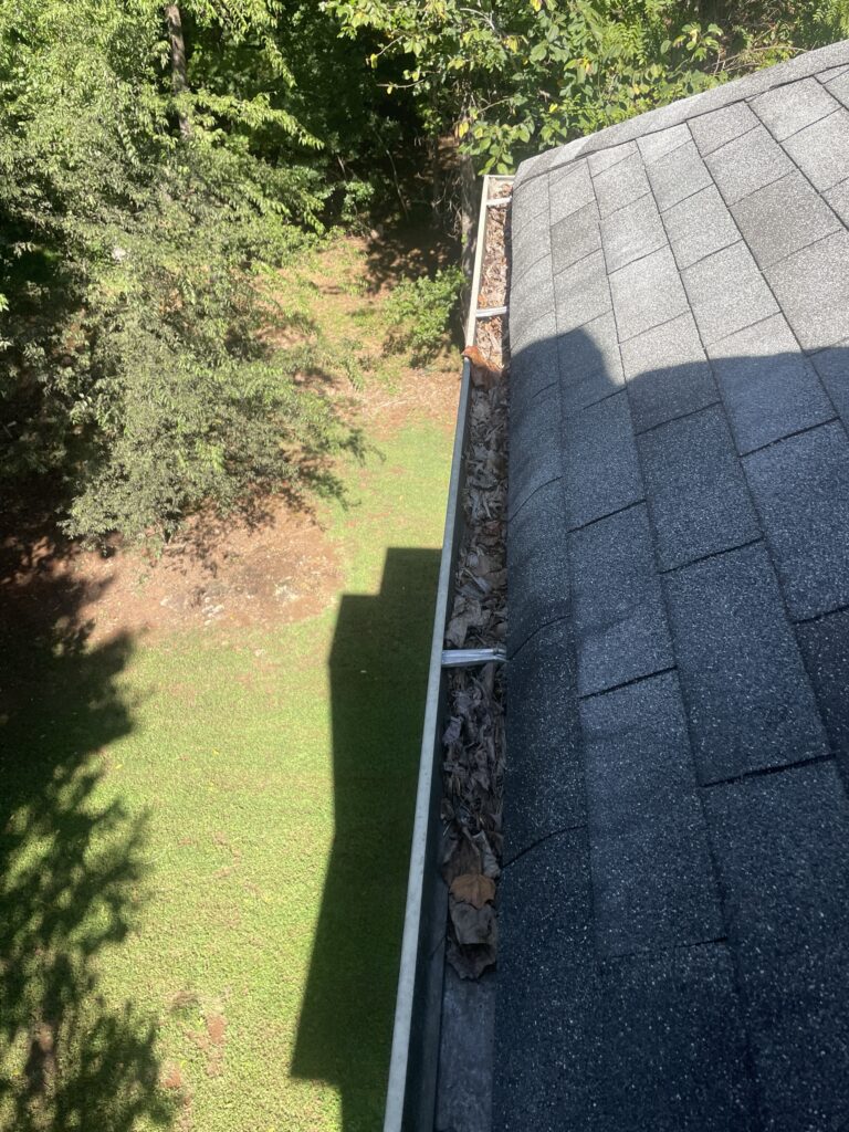 Gutter packed with leaves and debris before cleaning
