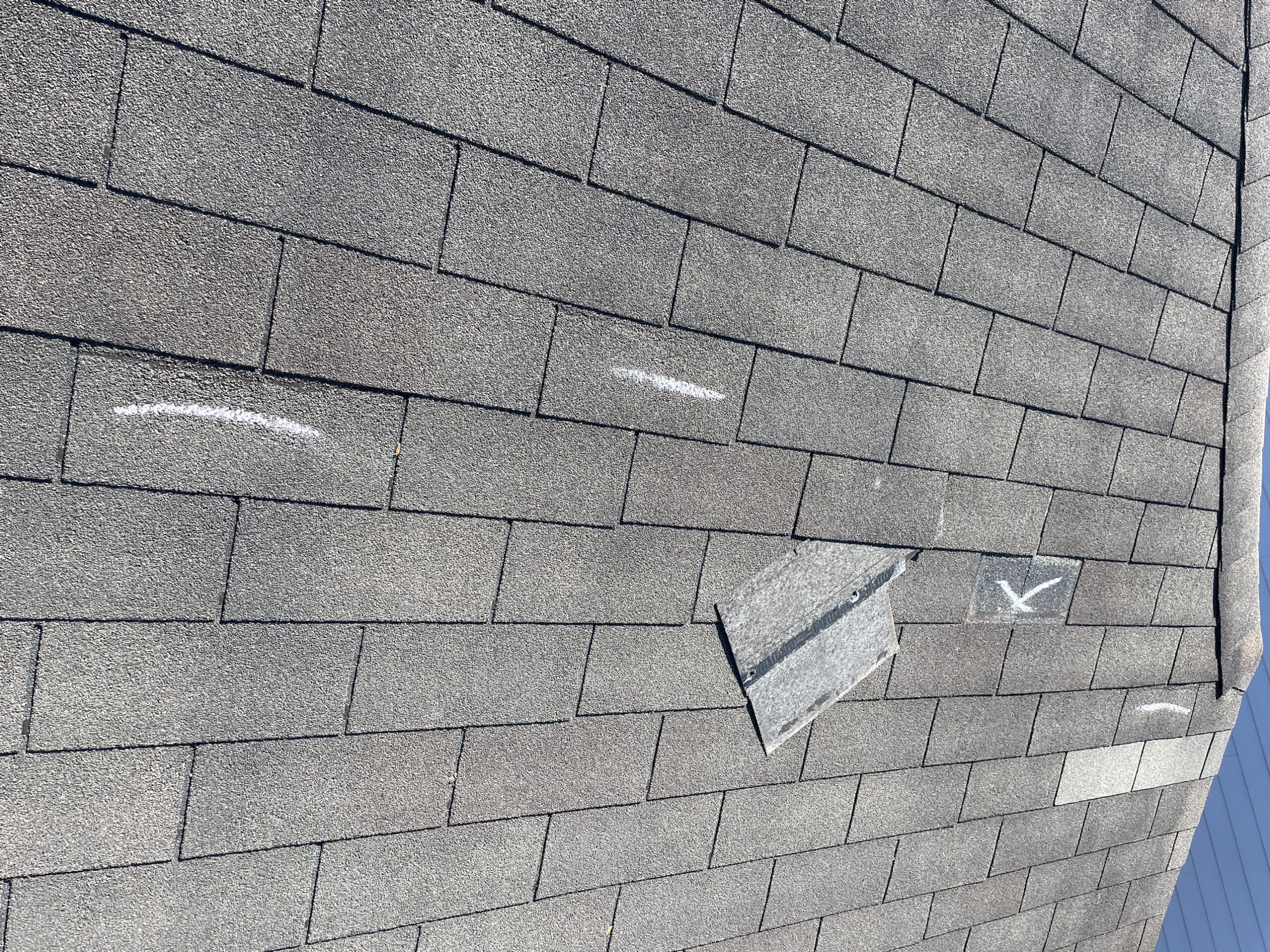 Wind-lifted shingle marked during a roof inspection